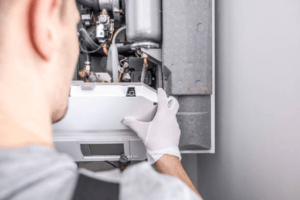 Close-up of a technician's gloved hands closing the front panel of a boiler after servicing its internal components