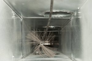 Specialized rotating brush removing dust and debris from the inside of an HVAC air duct.